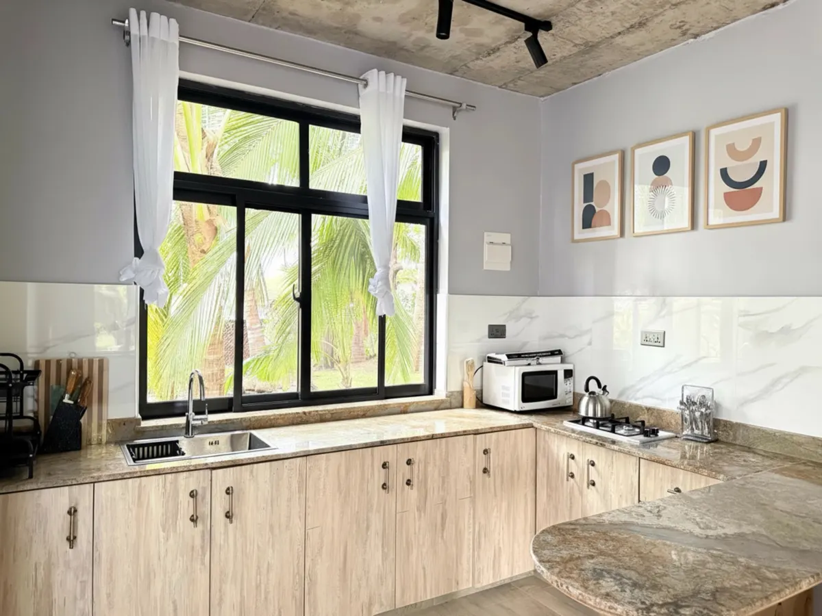 A fully equipped kitchen with stone counters and a garden-facing window
