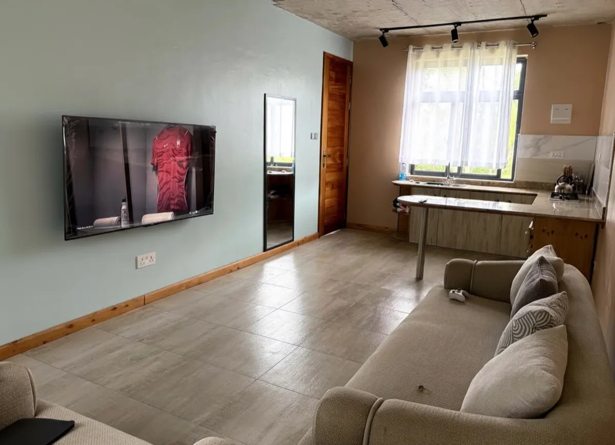 A cottage living area with lounge seating and an open kitchenette